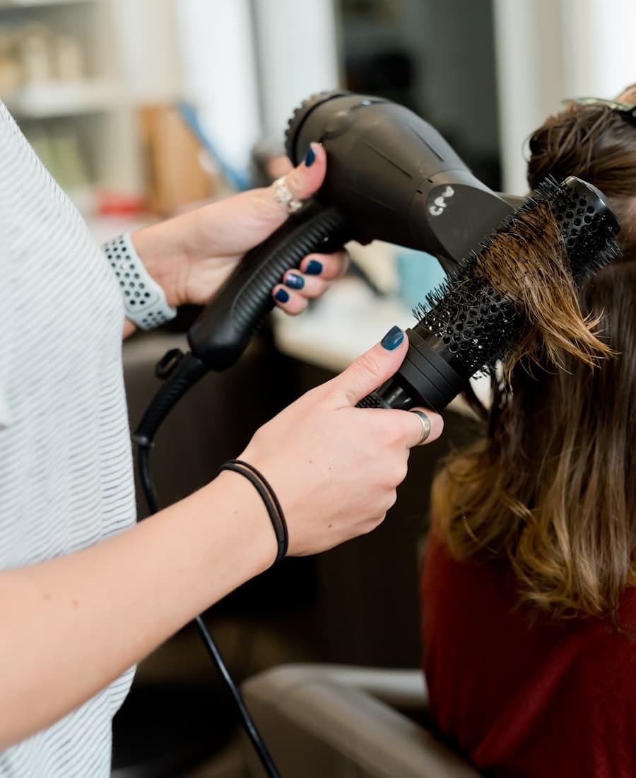 Coiffeurin stylt die Haare einer Kundin im Salon